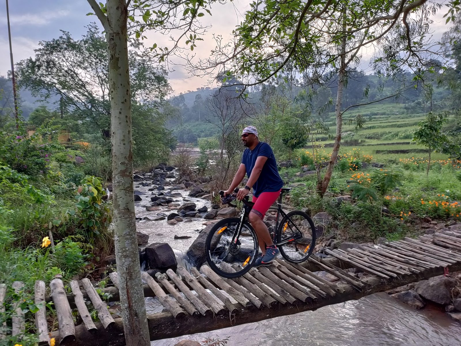 Cyclist crossing a wooden bridge in misty Araku